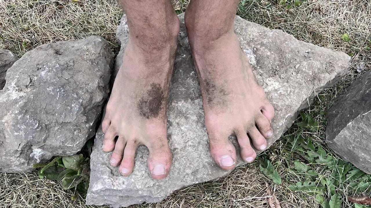 Bare feet standing on a rock outdoors.