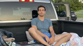 Portrait sitting in the bed of a pickup truck at sunrise.