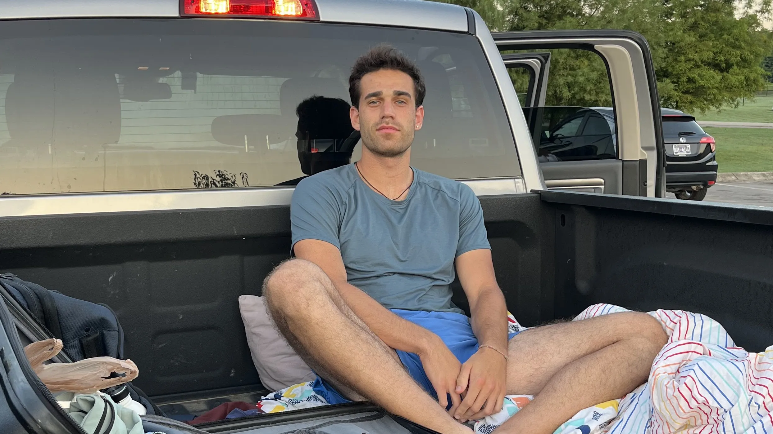 Portrait sitting in the bed of a pickup truck at sunrise.
